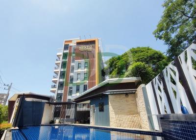 Modern building facade with swimming pool in the foreground and clear blue sky