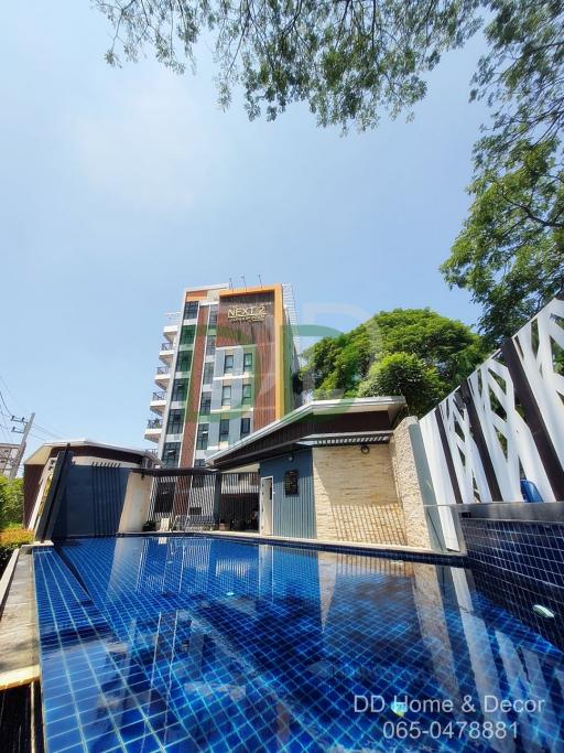 Modern building facade with swimming pool in the foreground and clear blue sky