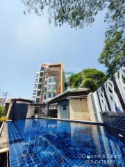 Modern apartment building with a swimming pool in the foreground and clear blue sky