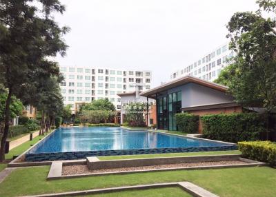 Spacious outdoor common area with swimming pool and well-maintained lawn at a residential complex