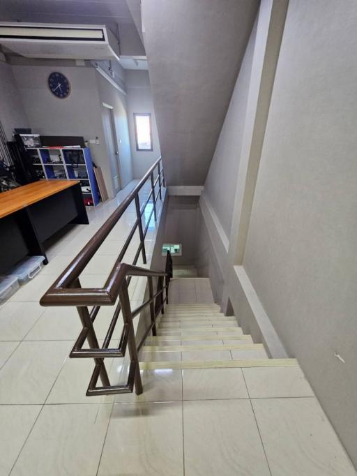 Bright and modern staircase interior with glossy tiled floors and wooden railing