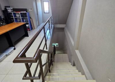 Bright and modern staircase interior with glossy tiled floors and wooden railing