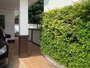 Driveway of a residential home with partial view of a car and lush green hedge