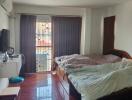 Spacious bedroom with glossy hardwood flooring and ample natural light from the large window