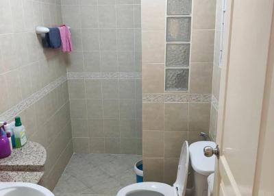 Small tiled bathroom with toilet and shower area