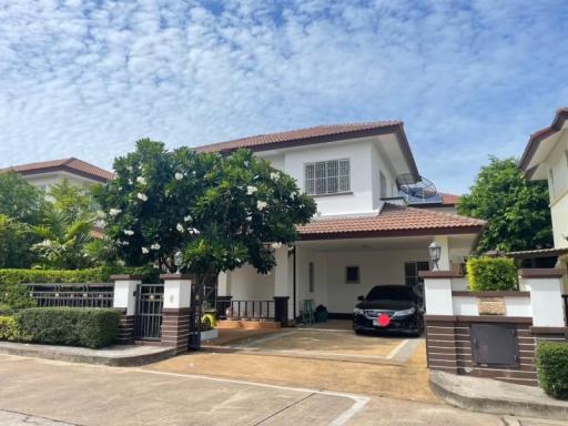 Spacious two-story house with a garage and lush greenery under a blue sky