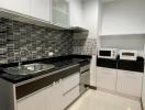 Modern kitchen with white cabinets and black backsplash