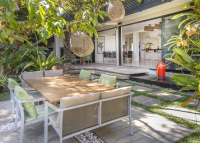 Outdoor dining space with large wooden table and comfortable seating in a lush garden