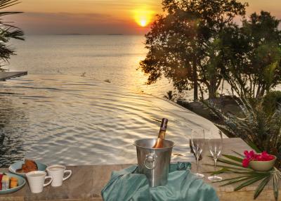 Luxurious infinity pool overlooking the ocean at sunset with refreshments