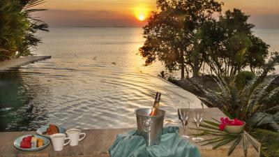 Luxurious infinity pool overlooking the ocean at sunset with refreshments