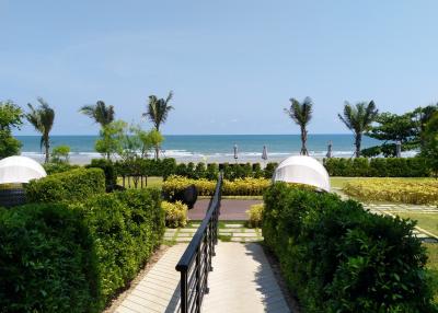 Oceanfront view from the property showing a pathway leading to the beach with palm trees and clear blue skies