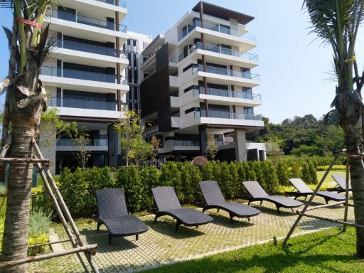 Modern multi-story residential building with lounge chairs and green lawn
