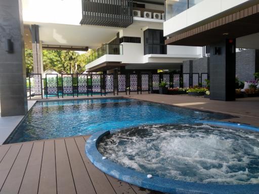 Modern outdoor swimming pool with adjacent jacuzzi and wooden deck