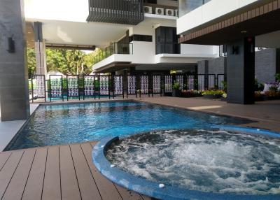Modern outdoor swimming pool with adjacent jacuzzi and wooden deck