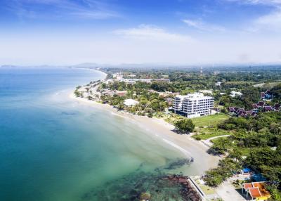 Aerial view of beachfront property with clear blue waters and surrounding greenery