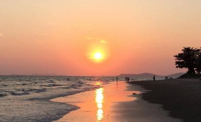 Sunset view at the beach with reflective shoreline and silhouettes of people