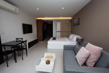 Modern bedroom with integrated living space, featuring a neat color scheme and contemporary furniture