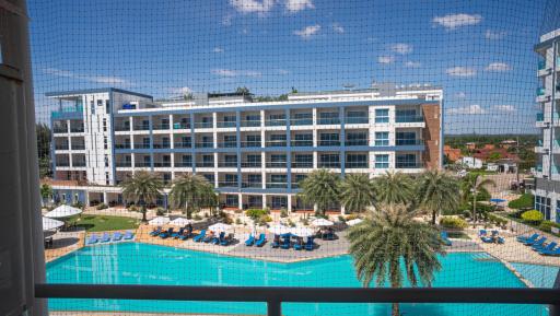 Scenic view of a resort-style pool and building from a property balcony with a safety net.