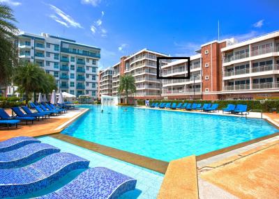 Swimming pool with lounge chairs and surrounding residential buildings in a sunny day
