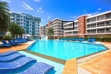 Swimming pool with lounge chairs and surrounding residential buildings in a sunny day