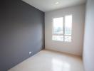 Empty bedroom with large window and gray accent wall