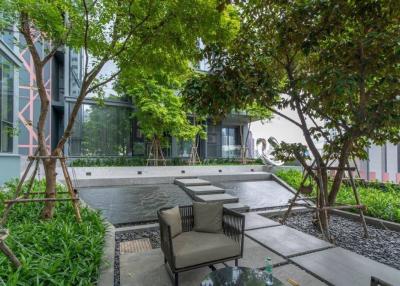 Modern outdoor seating area with green trees and building facade in the background