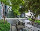 Modern outdoor seating area with green trees and building facade in the background