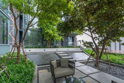 Modern outdoor seating area with green trees and building facade in the background