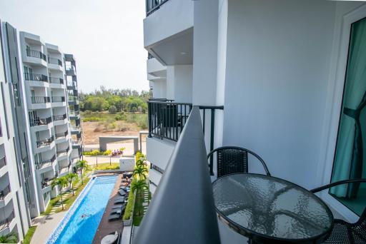 Spacious balcony overlooking a communal swimming pool within a modern apartment complex