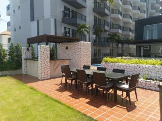 Modern outdoor communal area with poolside dining set and a pergola