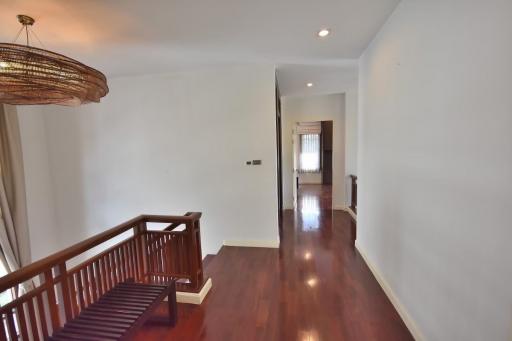 Spacious upper level hallway with hardwood flooring and elegant light fixture