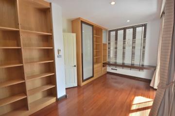 Spacious bedroom with wooden flooring and built-in shelves