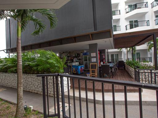 Covered outdoor patio area near residential building with seating and plant decorations