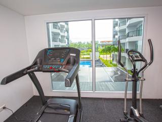 Home gym room with exercise equipment and view towards a pool