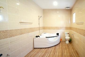 Spacious modern bathroom with a corner jacuzzi tub, toilet, and tiled flooring