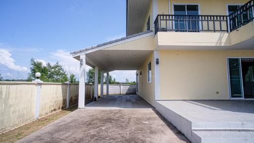 Spacious outdoor patio area of a modern two-story home with a balcony and a covered pathway