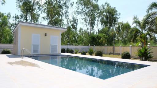 Private outdoor swimming pool with adjacent pool house and lush greenery