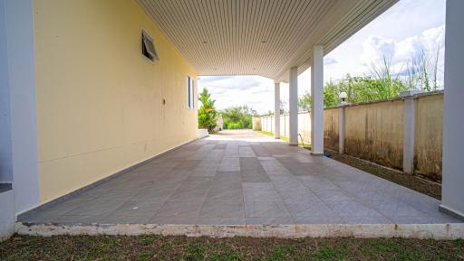 Spacious tiled patio with a covered area and open walls leading to the backyard