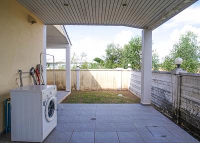 Covered patio area with washing machine and garden view