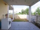 Covered patio area with washing machine and garden view