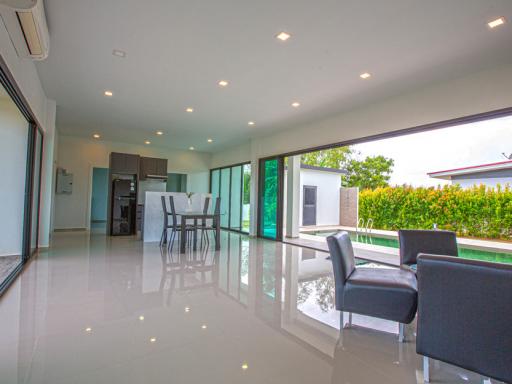 Spacious living area with dining table, modern kitchen, and sliding doors leading to the pool