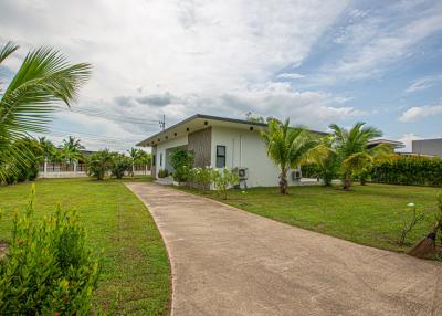 Single-story house with a well-manicured lawn and tropical landscaping