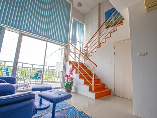 Bright and airy living room with staircase and balcony access