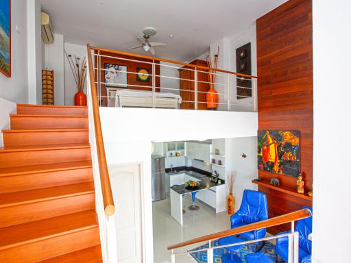 Interior view of a modern building with a focus on the staircase and the open kitchen area