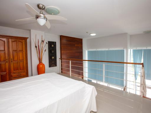 Spacious bedroom with modern ceiling fan, wood furniture and balcony access