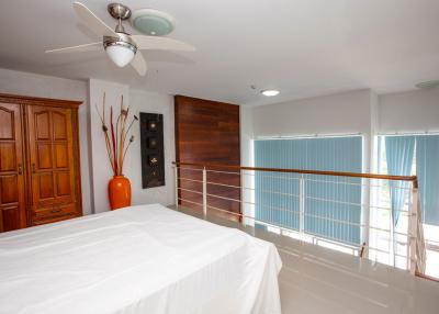 Spacious bedroom with modern ceiling fan, wood furniture and balcony access