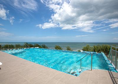 Luxurious infinity pool with sea view and spacious tiled patio under clear blue sky