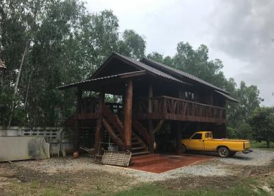 Rustic two-story wooden house with a yellow truck parked underneath