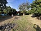 Spacious backyard with natural surroundings and a person standing in the distance