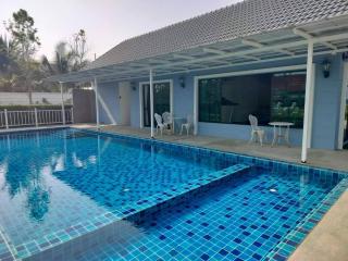 Private outdoor swimming pool with patio furniture and adjacent house